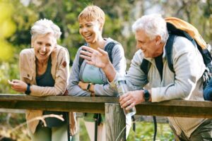 elderly friends laughing together while traveling through a park