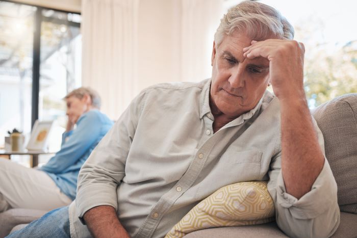 Senior couple sitting on a sofa experiencing conflict in their relationship
