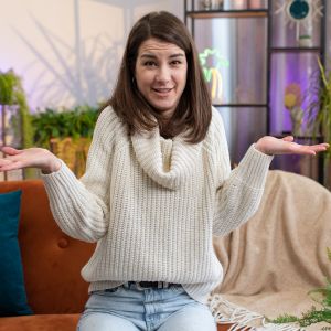 A young lady posing in front of the camera with booth hands bent palm faced up at near shoulder level