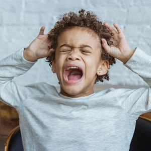 Child covering ears and shouting, representing sound sensitivity or hyperacusis